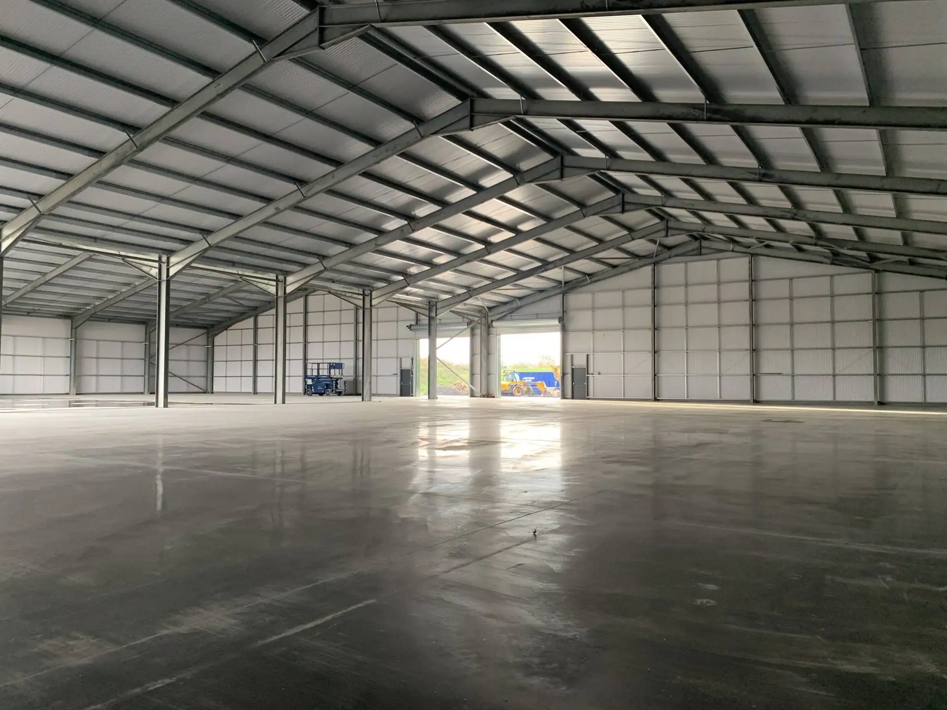 Large empty industrial warehouse with a steel portal frame and a polished concrete floor