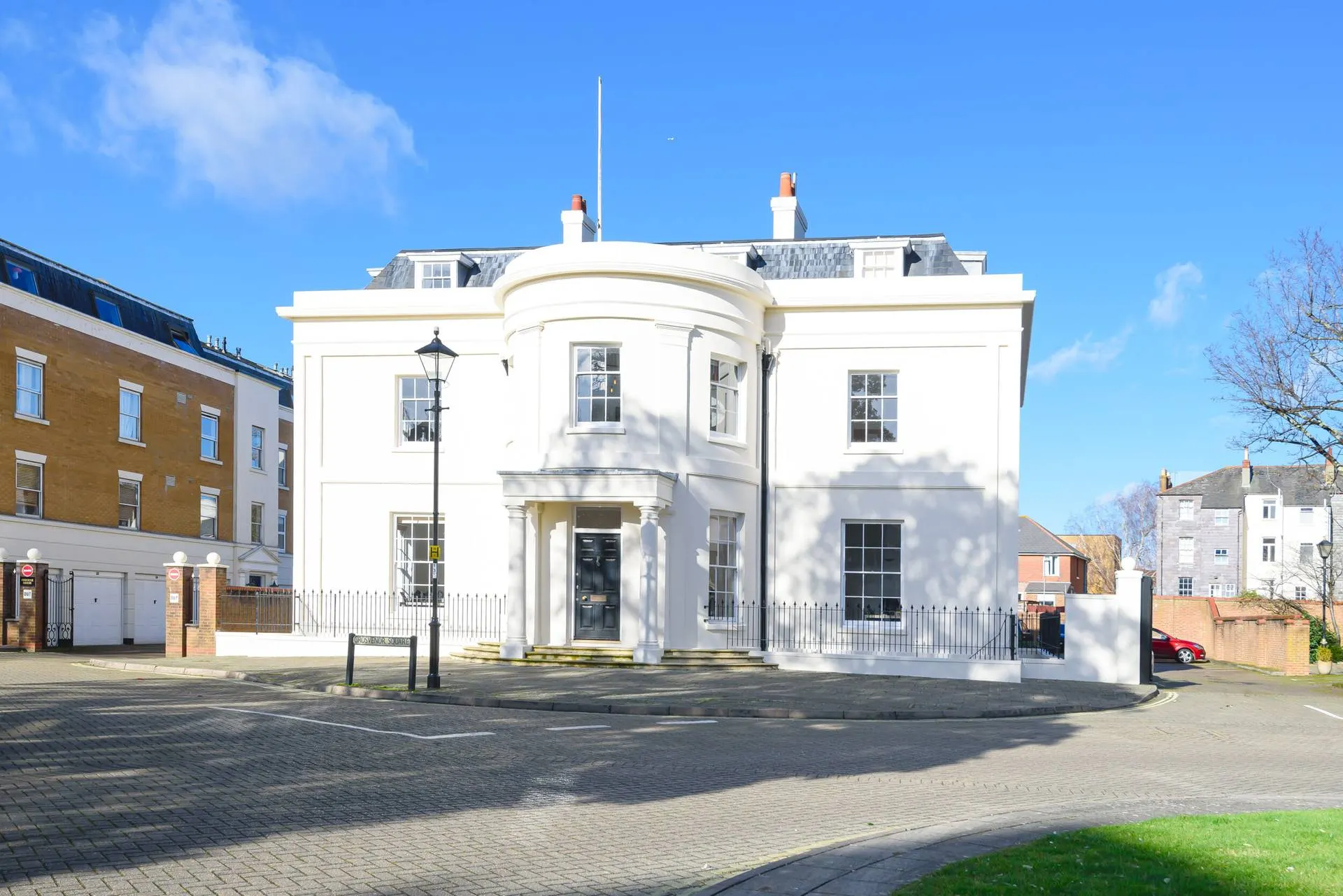 White Georgian-style office building with a curved bay on a sunny street
