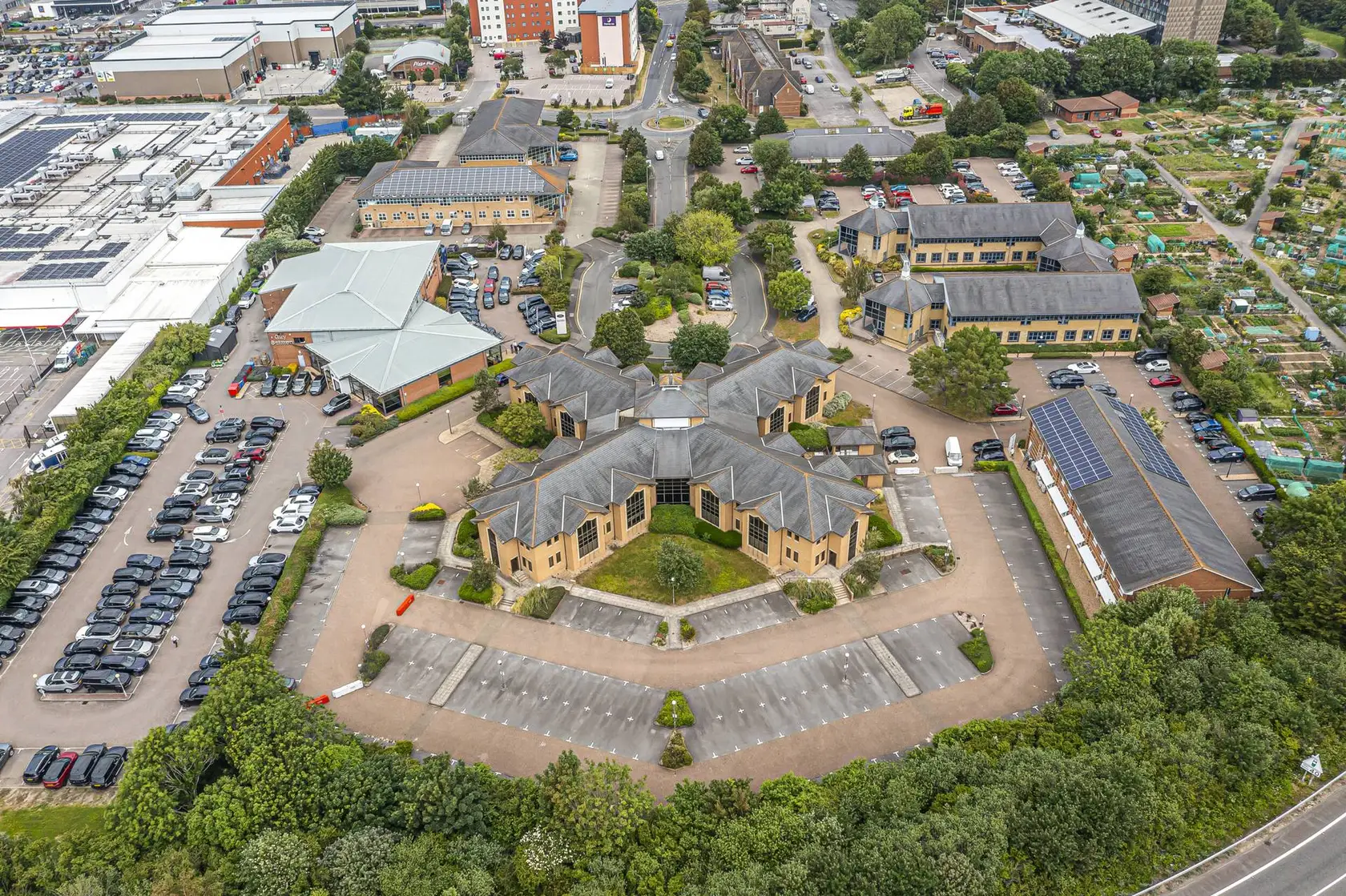 Aerial view of a business park with a car park, landscaped grounds and pitched-roof office buildings