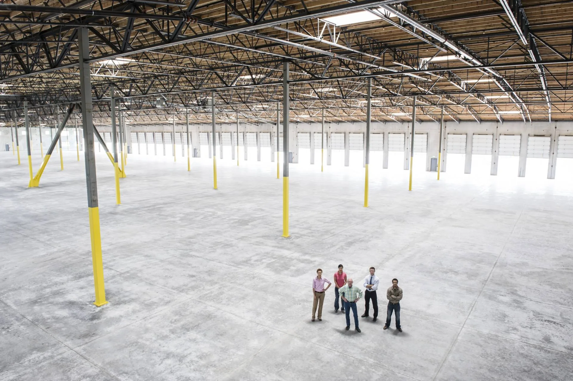 Group of people standing together on the floor of a large empty warehouse