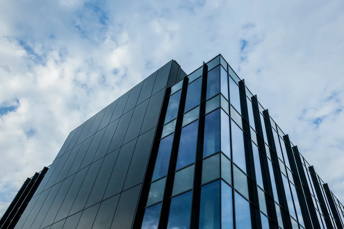 Modern glass and dark panel office building against a cloudy sky
