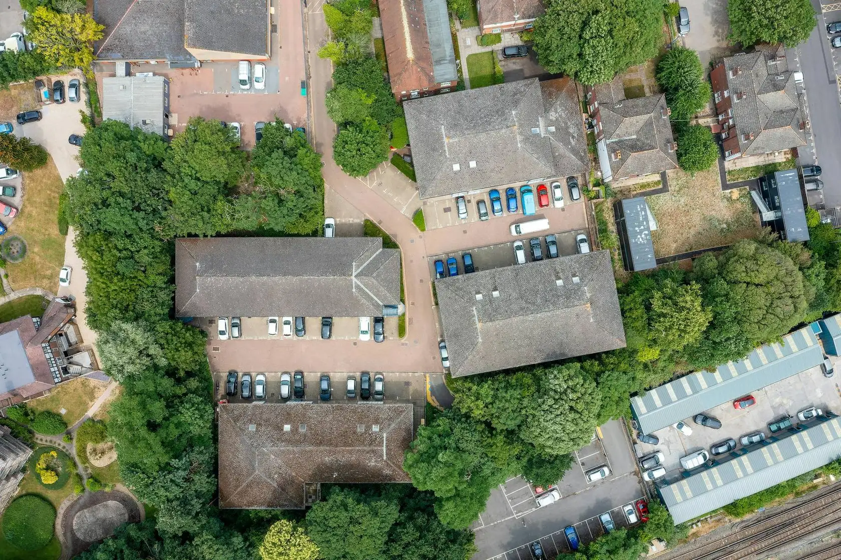 Aerial view of a business centre with grey-roofed office buildings, car parks and trees
