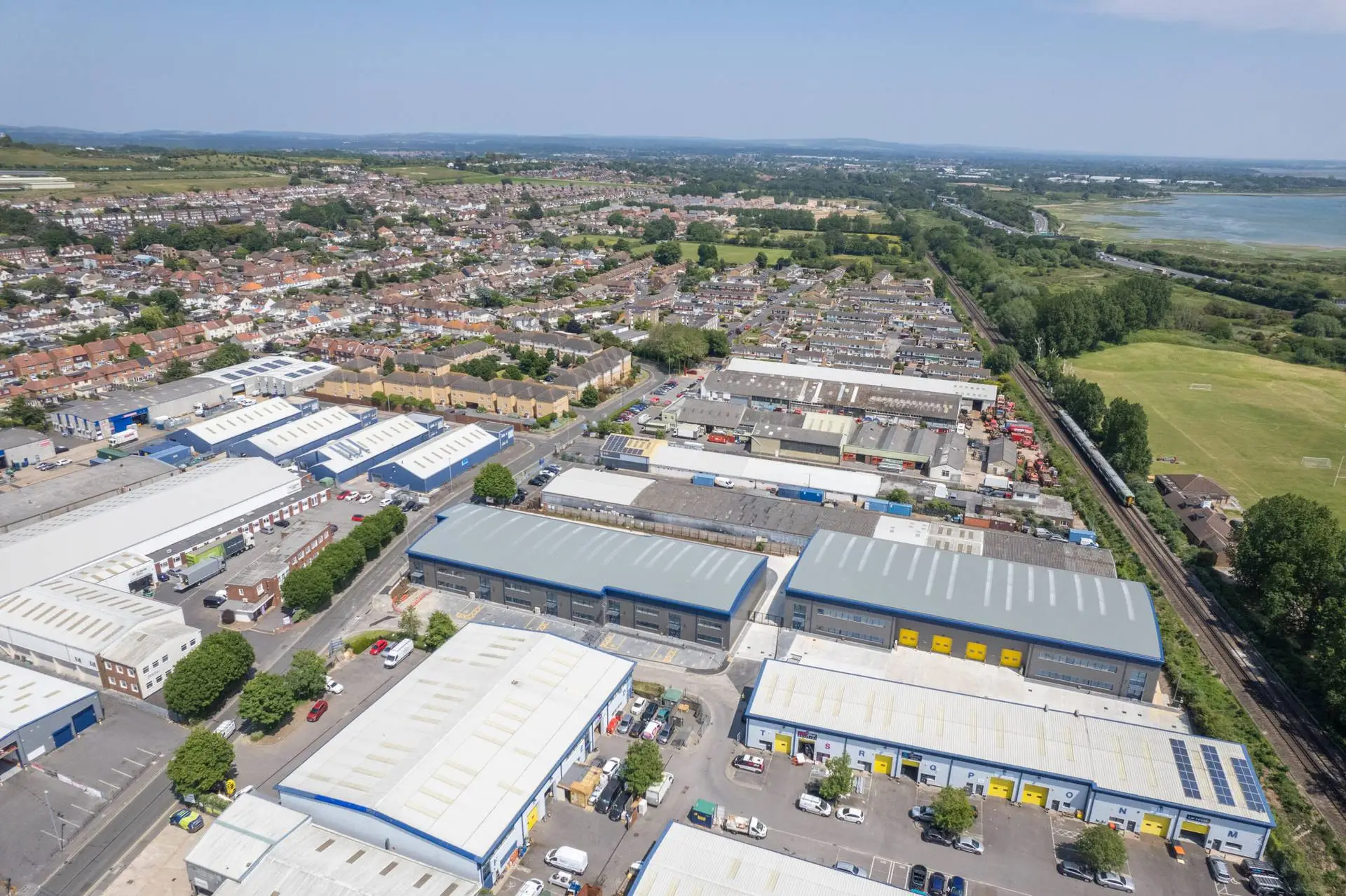 Aerial view of a town with industrial units and warehouses beside a railway line and the coast