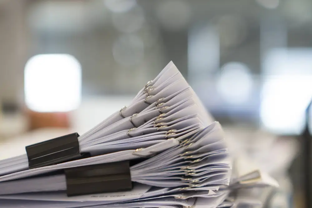 Stack of bundled paper documents held with black clips