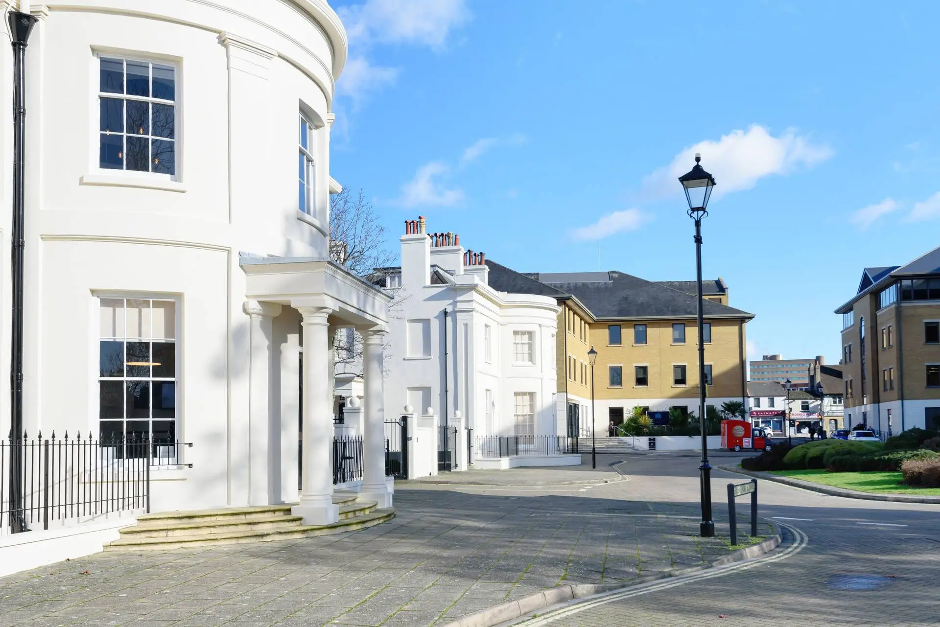 White Georgian-style buildings on a sunny street with a Victorian lamp post