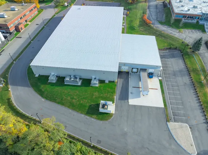Aerial view of a white warehouse unit with a car park and landscaped grounds