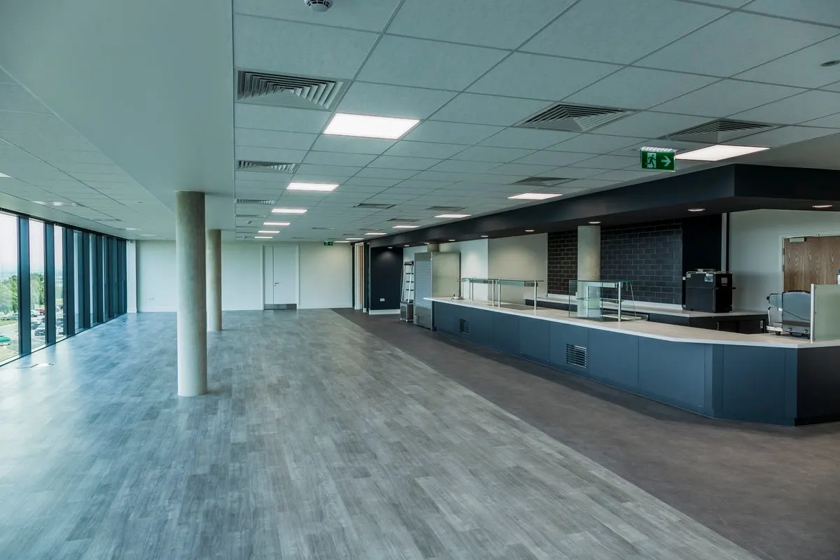 Empty open-plan office floor with a long counter, columns and large windows