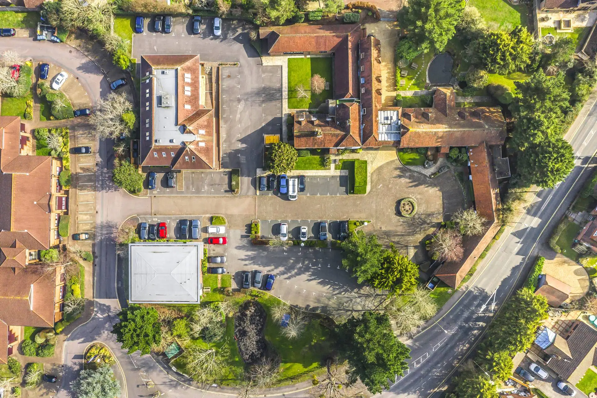 Aerial view of office buildings, car parks and red-tiled roofs beside a road